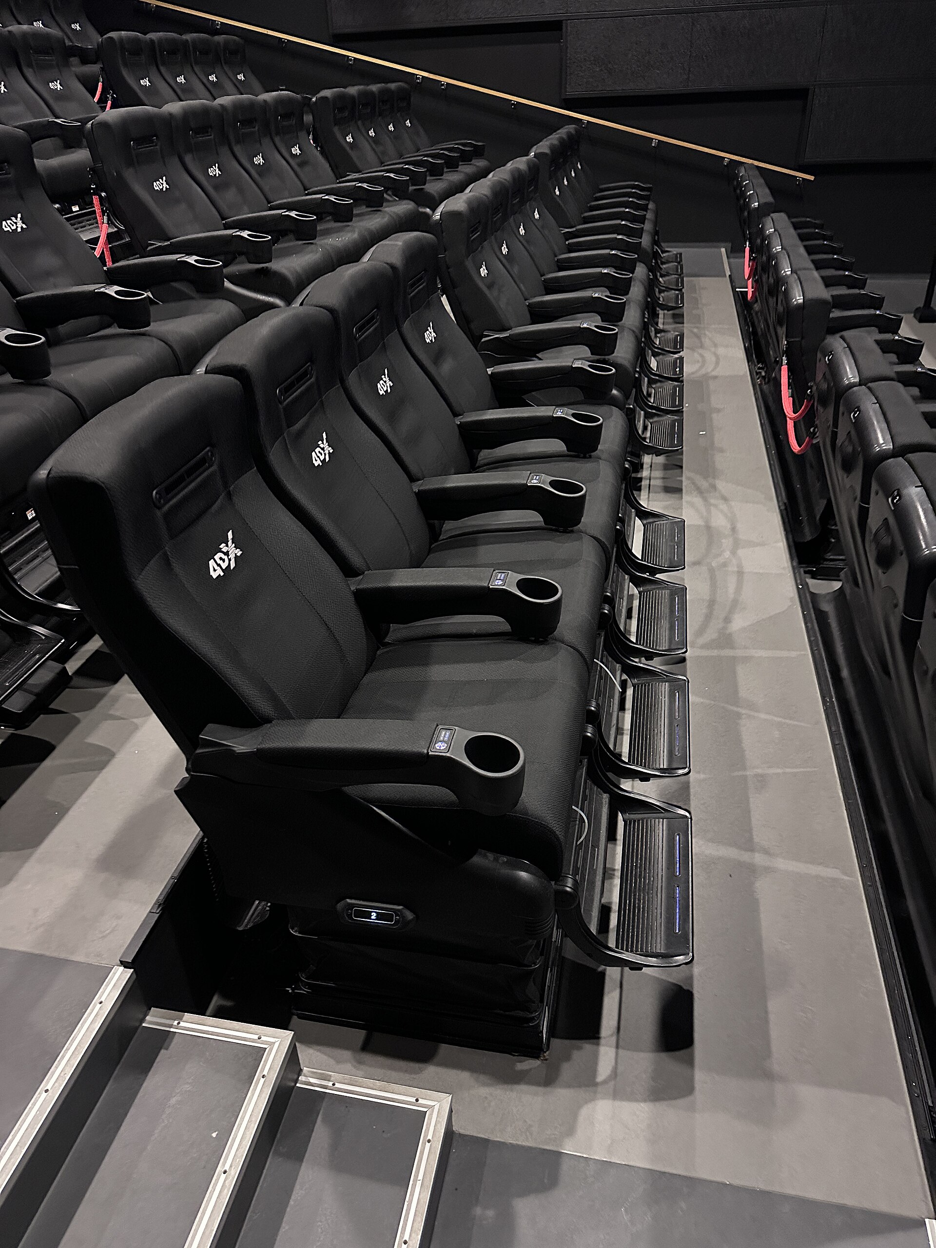 4DX seats in a cinema auditorium (bench rows in a movie theater hall) in Norway. Seating providing motion and environmental effects synced with the on-screen action.